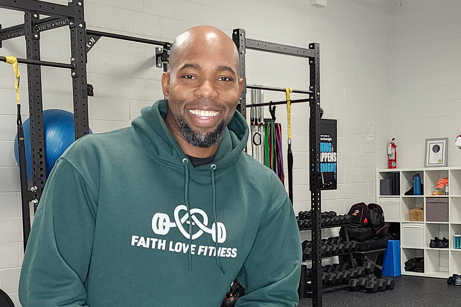Gbenga Adeniyi in the studio, wearing a Faith Love Fitness hoodie