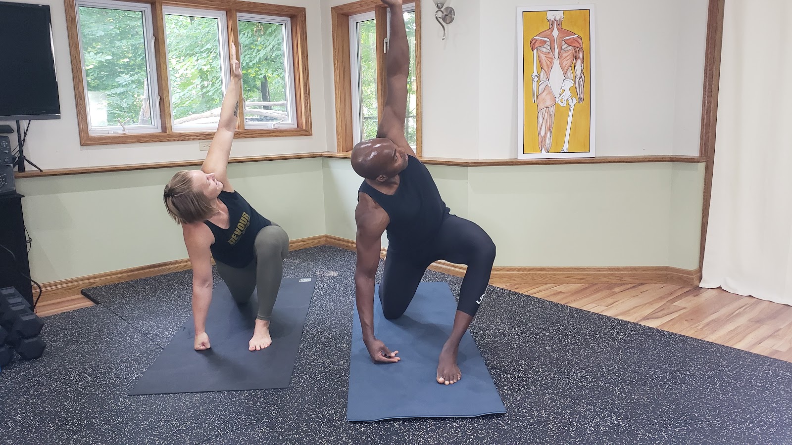 Gbenga and a member working through a kneeling side stretch