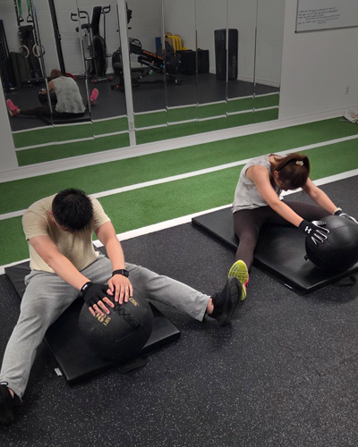 Two members training side by side with medicine balls